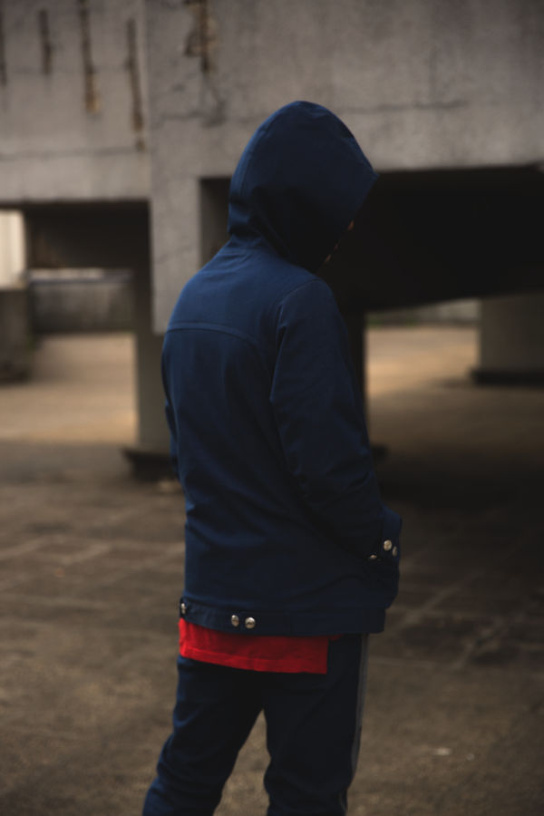 Portrait masculin en sweat à capuche bleu contre un mur en béton — photographie de Claude Quéré