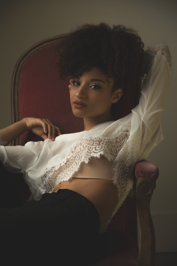 Portrait dans un fauteuil rouge, haut blanc ouvert — photographie de Claude Quéré