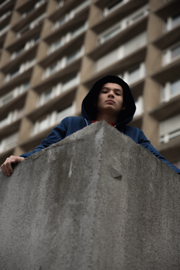 Portrait appuyé contre un mur en pierre, regard détourné — photographie de Claude Quéré